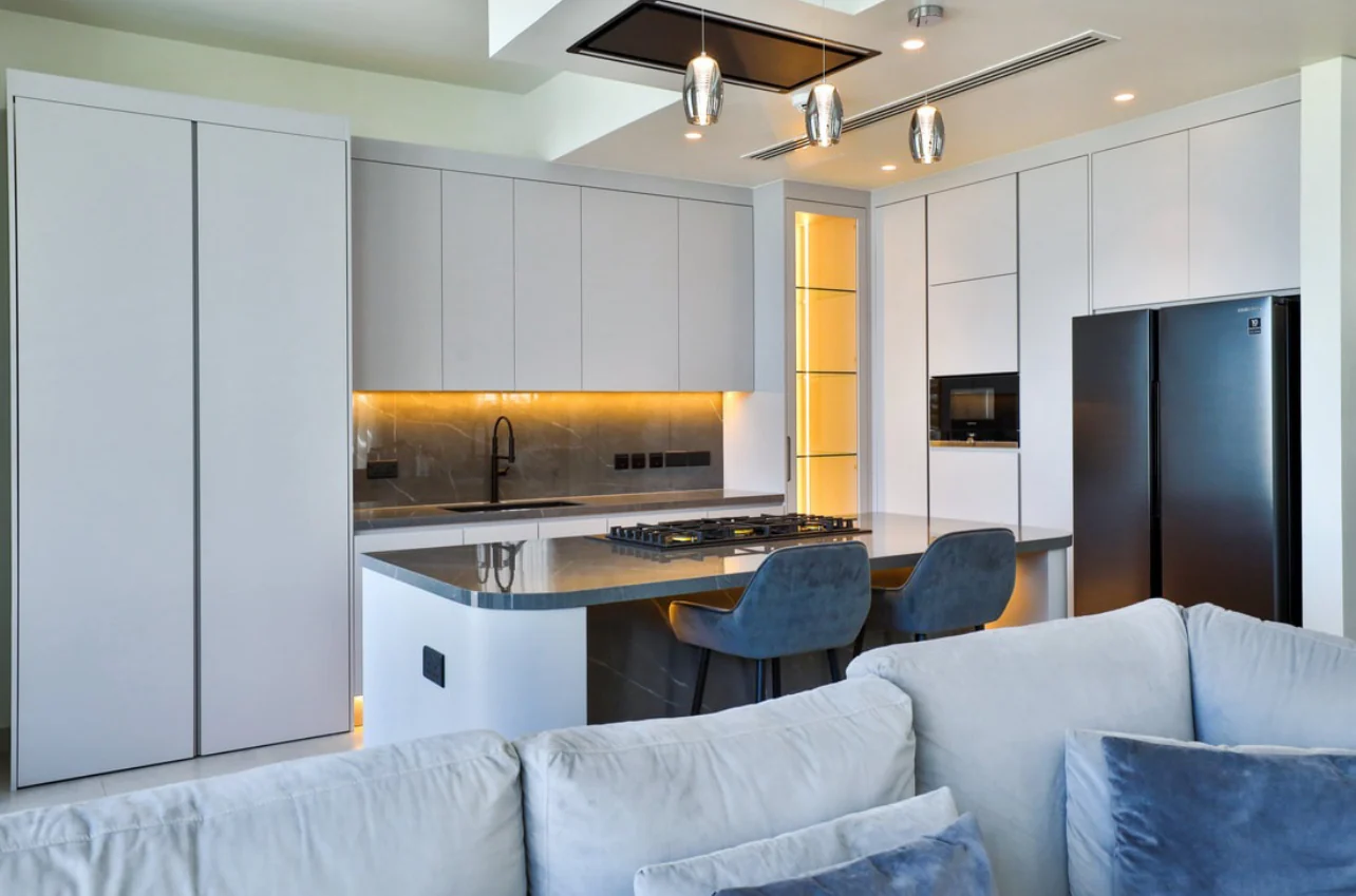 Full-height white kitchen cabinets with integrated storage and a contrasting stone island by Time Furniture