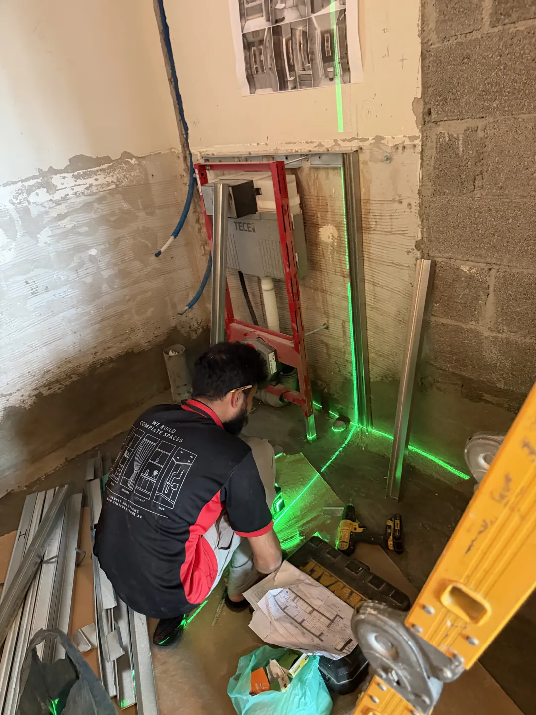 Time Furniture tiling installer setting out bathroom finishes with a laser level